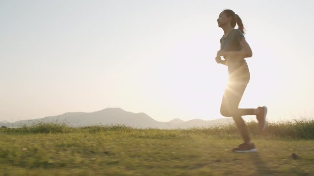 Young Asian women are exercising outdoor running with a mountain background. When the sunset or sunrise in Thailand in summer, Concept healthy running and outdoor exercise, Tracking dolly shot