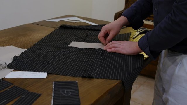 Handsome middle aged man Fashion designer hands placing interfacing fabric before starting the designing of the flap pockets of this jacket.