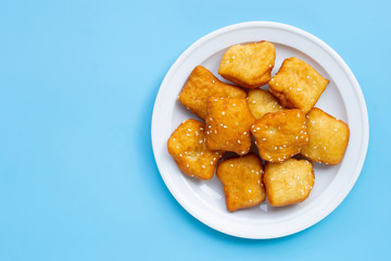 Chinese deep fried dough sticks with white sesame seeds on blue background.