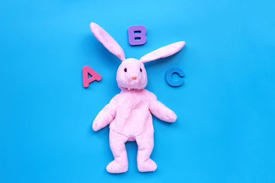 Rabbit toy with english alphabet on blue background. Education concept, Copy space