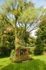 Terrace with a beautiful garden, table, chairs, sun umbrellas and trees