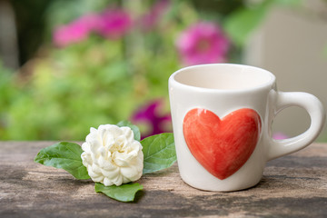 Cup coffee, jasmine flower on wooden table.