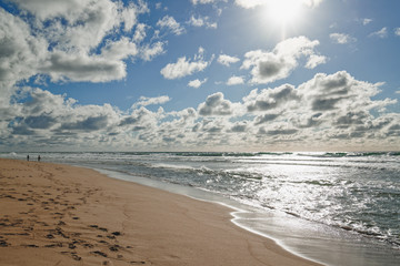 Scenic seascape. Sand beach, ocean, and cloudy sky background