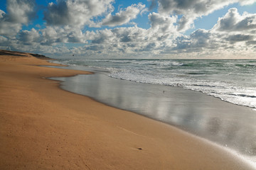 Dramatic beach scene. Stormy ocean, empty sand beach, and cloudy sky on background