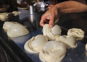 Hand pick up roti bread dough and prepare to cook