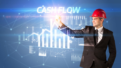 Handsome businessman with helmet drawing CASH FLOW inscription, architecture business plan concept
