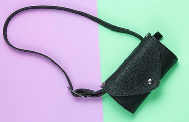 Stylish belt bag on green pink pastel background. Top view