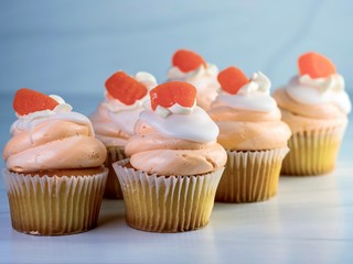 6 vanilla cupcakes with orange swirled frosting and an orange gum drop on top.  Festive, delicious, dessert for a celebration.