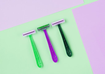 Minimalistic beauty concept. Epilation. Plastic colored razors on pastel background. Top view