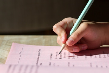 Closeup of kid's hand holding a pencil writing on a workbook.