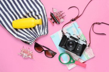 Traveler accessories, retro camera on pink background. Trip on the beach, vacation. Summer...