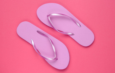 Trendy beach pink flip flops on pink paper background. Top view