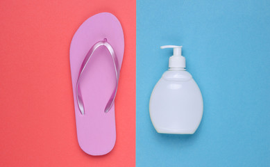 Beach accessories. Fashionable beach pink flip flops, sunblock bottle on coral blue paper...