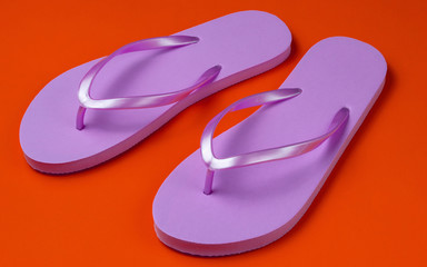 Fototapeta premium Trendy beach pink flip flops on orange background.