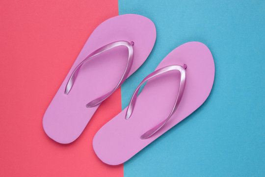 Trendy beach pink flip flops on coral blue paper background. Top view