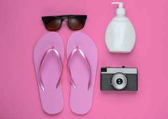 Summer still life. Beach accessories. Fashionable beach pink flip flops, retro camera, sunblock...