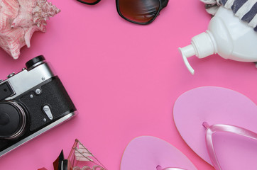 Summer still life. Beach accessories. Fashionable pink flip flops, bag, retro camera, sunblock...