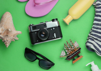 Summer still life. Beach accessories. Fashionable pink flip flops, bag, retro camera, sunblock...