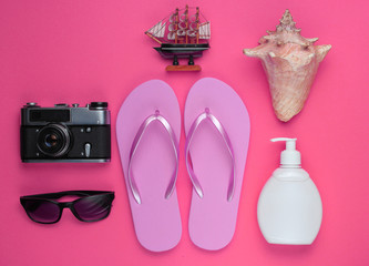 Summer still life. Beach accessories. Fashionable pink flip flops, retro camera, sunblock bottle,...