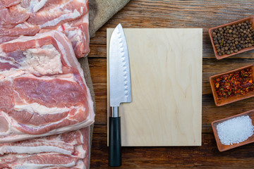 bacon pieces on a wooden background and burlap,spices and a cutting Board with a knife, upper...