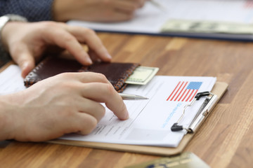 Male hands in suit lie on application for usa visa. Registration in the system embassies. Priority...