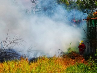 Fototapeta premium Fireman using water and extinguisher to fighting with fire flame in an emergency situation.,There is dirty smoke floating over the area.