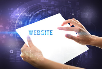 Hand holdig futuristic tablet with WEBSITE inscription, new technology concept