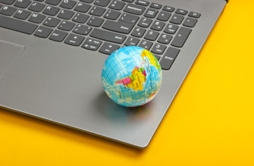 Global network, internet, online shopping.  Laptop and globe on yellow background.