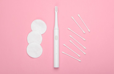 Flat lay composition of hygiene products. Toothbrush, cotton pads, ear sticks on pink pastel background. Top view