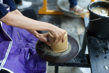 Hand of medieval craftsman female makes a pot of clay