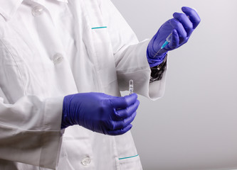 a medical worker with an ampoule of medicine and a syringe is going to be vaccinated
