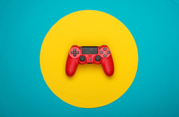 Red gamepad on blue  background with yellow circle. Gaming, leisure and entertainment concept. Top...