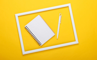 Notebook and pen on yellow background with white frame. Studio shot. Creative flat lay. Top view....