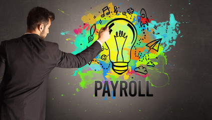 businessman drawing colorful light bulb with PAYROLL inscription on textured concrete wall, new business idea concept