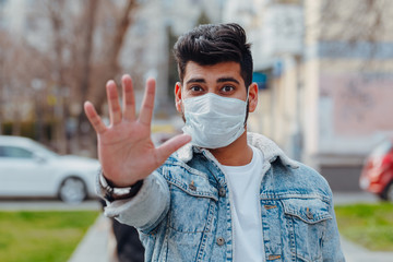 A fashionably dressed young Indian man in a medical mask walks on the street during the 2019-nCoV pandemic. hygienic mask to prevent infection, airborne respiratory illness such as flu