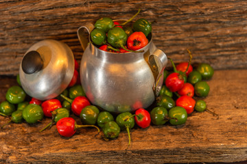 Goat pepper (Apsicum chinense) scattered in metal utensil on a woody background