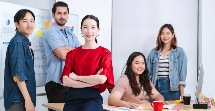 Smart Asian Startup Small Entrepreneur  Standing Confident Portrait With  Friends Partner Casual Meeting Brainstorm With White Board And Business Financce Paper Chart Anslysis In Office Background