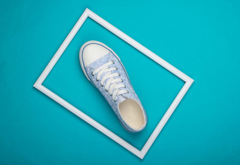 One Retro sneaker on blue background with white frame. Minimalism. Top view