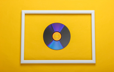 CD disk in white frame on yellow background. Top view