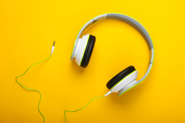 Stylish wired stereo headphones on yellow background. Music lover. Gadgets. Top view.
