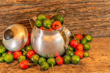 Goat pepper (Apsicum chinense) scattered in metal utensil on a woody background