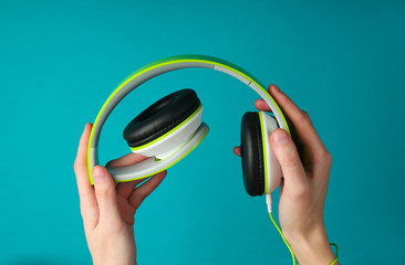 Female hands fold folding stereo headphones on a blue background