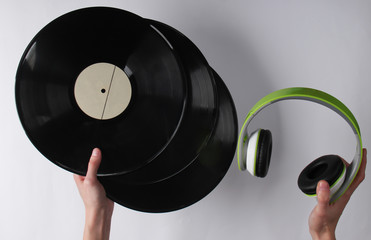 Hands hold vinyl records and headphones on a white background. Retro media, 70s