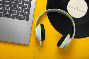 Laptop with headphones, vinyl record on yellow background. DJ concept. Top view. Flat lay