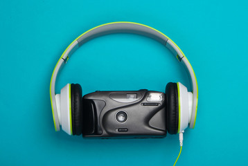 Stereo headphones with a retro film camera on a blue background. Top view
