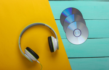 Stereo headphones, cd discs on blue wooden table. Music lover. Retro 90s. Top view.