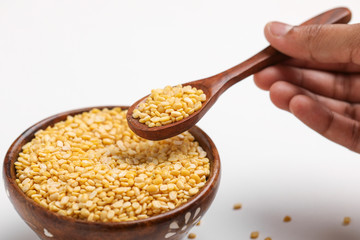 yellow moong mung dal lentil pulse bean in wooden and spoon bowl on white background