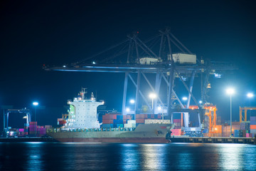 Obraz premium Container ship is berthing with cargo operation at night at sea port.