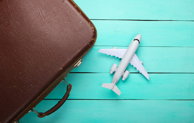 Travel concept. Old luggage and airplane figurine on blue wooden floor. Flight voyage, trip,...