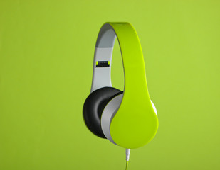 Modern wired stereo headphones on a green background.